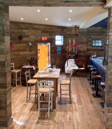 Cozy rustic restaurant interior with wood paneling and tables.